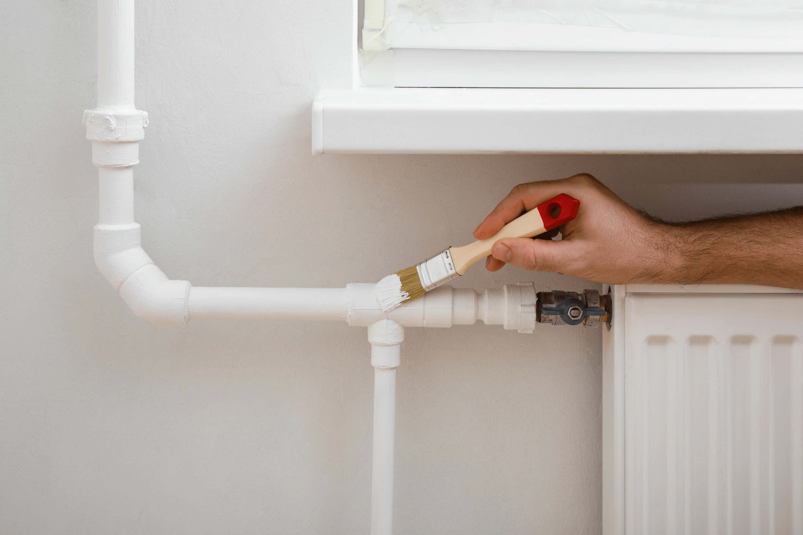 Homeowner Painting Radiator Pipes In White To Match